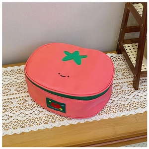 Detail of tomato-shaped nylon pouch with smiling face, green leaves and zipper closure