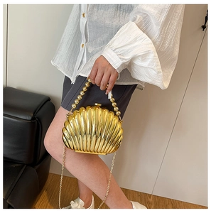 Close-up of gold shell clutch bag with pearl bead handle and elegant metal chain strap