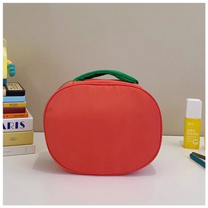 Detail of cute tomato-shaped nylon storage bag with green handle on a soft home background