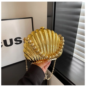 Detail of golden shell-shaped clutch with radial texture and beaded metal edges