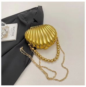 Close-up of golden shell-shaped evening bag with metallic finish on dark grey blazer
