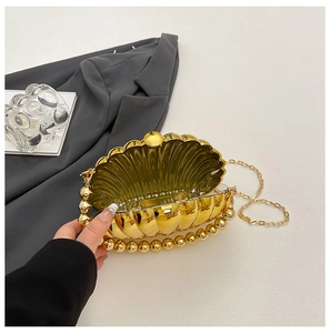 Detail of golden acrylic shell clutch bag opening with luxury bead handle and chain