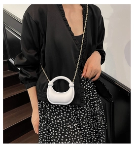 Mini borsa a mezzaluna bianca con manico circolare e catena dorata su abito floreale