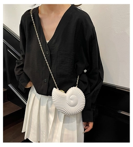 Detail of white nautilus shell acrylic clutch with elegant golden metal chain strap