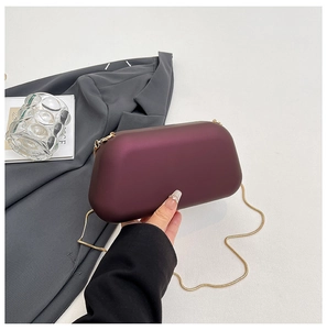Détail de pochette de soirée prune avec chaîne dorée sur fond de blazer gris élégant