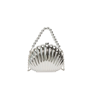 Detail of silver shell-shaped evening bag featuring bead handle and metal chain strap