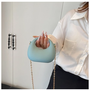 Détail du sac à main en acrylique bleu clair avec poignée ronde et bandoulière chaîne dorée