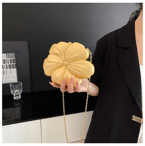 Detail of creative gold flower evening bag with elegant metal chain on black blazer