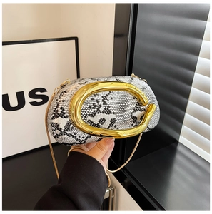Détail d'une pochette en acrylique motif serpent avec fermoir C doré et chaînette