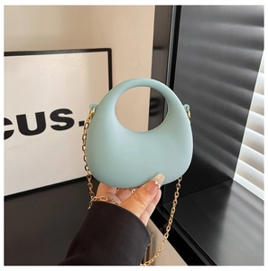 Détail du sac croissant en acrylique bleu clair avec chaîne dorée et fini silicone mat