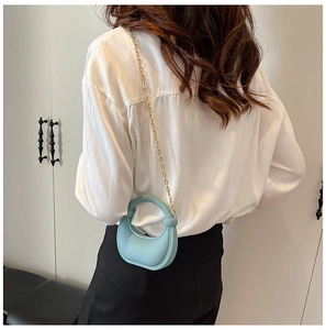 Vista posteriore di una modella con mini borsa in acrilico azzurro e tracolla a catena d'oro
