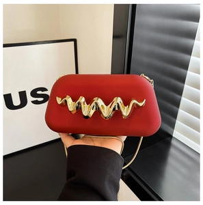Détail de la pochette rouge minimaliste avec décoration ondulée dorée et bandoulière
