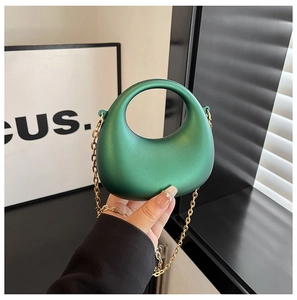 Détail du sac croissant en acrylique vert avec finition mate et chaîne en métal doré