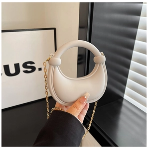 Dettaglio di una mini borsa a mezzaluna bianco crema con tracolla a catena dorata