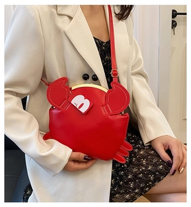 Detail of red crab-shaped crossbody bag with gold metal clasp and high-gloss leather finish