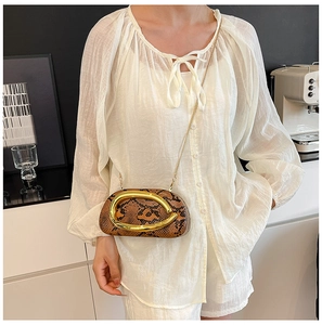 Détail du mini sac pochette à motif serpent avec poignée en C dorée et bandoulière chaîne