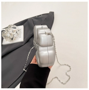 Detail of silver bow-shaped acrylic evening bag with a metallic textured chain strap