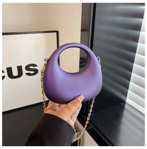 Gros plan d'un sac à main croissant violet en acrylique avec bandoulière chaîne dorée
