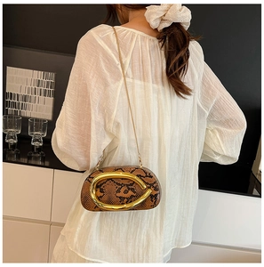 Détail d'un sac à bandoulière chic imprimé serpent avec une poignée anneau en métal doré