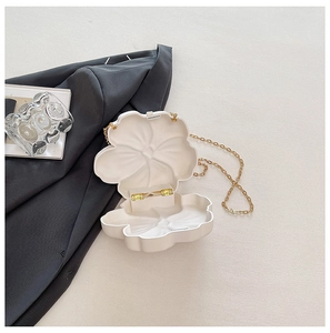 Detail view of white flower acrylic clutch bag interior with golden metal chain and hinge