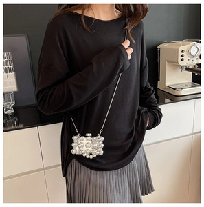 Mini acrylic chain bag with pearl embellishments worn as a stylish crossbody accessory
