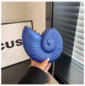 Dettaglio della borsa a conchiglia blu scuro con superficie testurizzata e catena d'oro