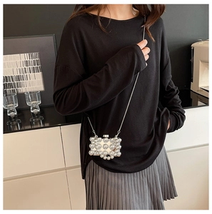 Mini silver clutch bag with beaded texture styled with a black outfit and gray skirt