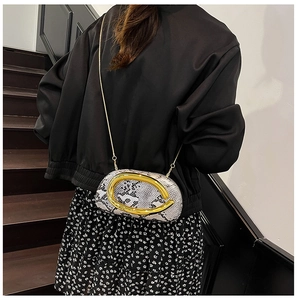Détail du sac de soirée motif python avec poignée dorée et bandoulière chaîne sur modèle