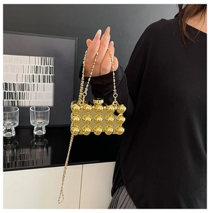 Detailed view of a gold metallic evening clutch with 3D spherical studs and chain strap