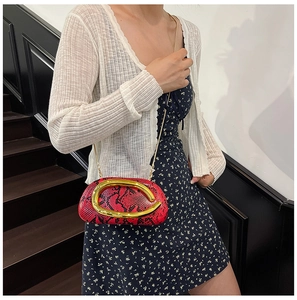 Détail de la texture serpent rouge et noir avec boucle dorée sur le sac de soirée