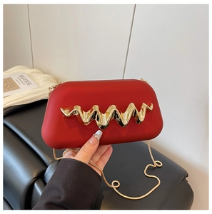 Détail de la pochette rouge avec boucle dorée et fine chaîne sur fond artistique