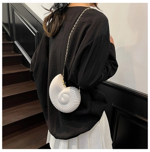 Elegante borsa a tracolla a forma di conchiglia con catena dorata su un outfit minimalista