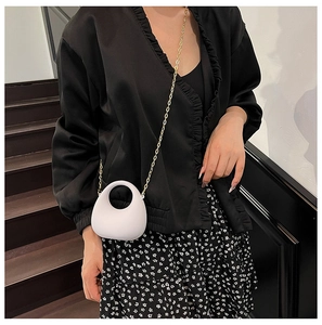Gros plan d'un mini sac demi-lune blanc en acrylique avec bandoulière chaîne dorée
