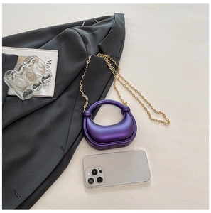 Dettaglio mini borsa a mezzaluna viola metallizzato con catena dorata su blazer grigio