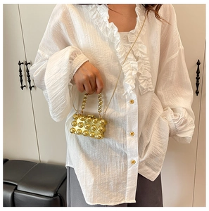 Detailed view of a mini gold pearl handbag with metallic studs and elegant chain strap