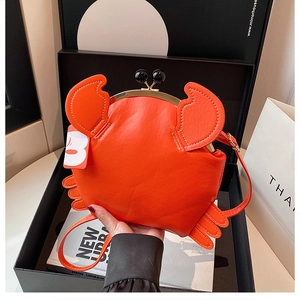 Detail of creative orange crab crossbody bag featuring golden clasp and leather texture