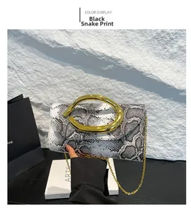 Close-up of black and white snakeskin clutch bag with metallic gold ring handle and chain