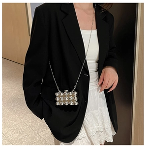 Silver mini acrylic box bag with metallic studs worn over a black blazer and white skirt