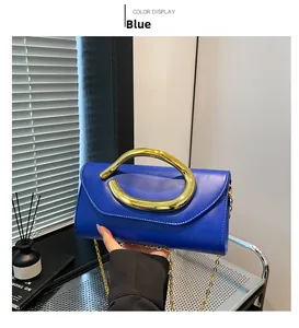 Detail of blue leather clutch with oversized round gold metal handle and chain strap