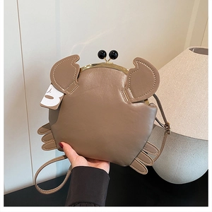Detail of creative khaki crab shaped crossbody bag with gold metal clasp and PU leather texture