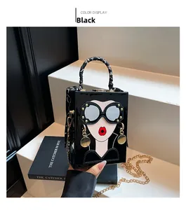 Detailed view of structured black crossbody bag with cartoon face and scarf handle
