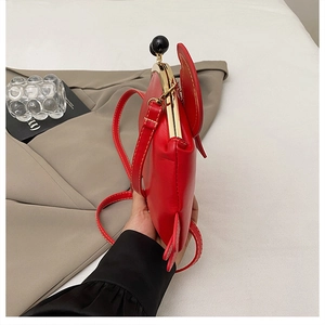 Detail of red vintage clasp handbag featuring round ear design and golden frame closure