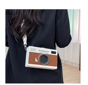 Detail view of stylish camera-shaped crossbody bag with white and brown leather contrast