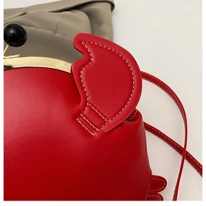 Close-up of red crab-shaped bag featuring golden metal clasp and black bead closure