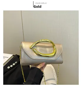 Detail of elegant gold clutch with distinctive metallic handle and fine chain strap