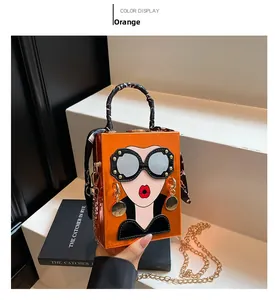 Detail of orange patent leather handbag with funny art face portrait and silk scarf handle
