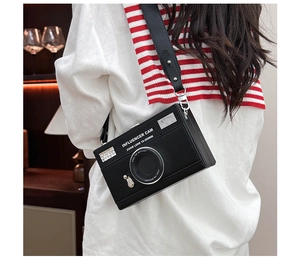 Detail of a black camera-shaped crossbody bag with influencer cam print and wide strap