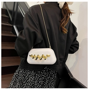 Détail de la pochette rigide blanche avec une décoration sculpturale en métal doré ondulé
