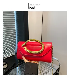 Detail of red leather evening clutch with large gold semicircular handle and chain