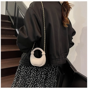 Mini borsa da sera in acrilico crema con catena dorata indossata da modella sulle scale